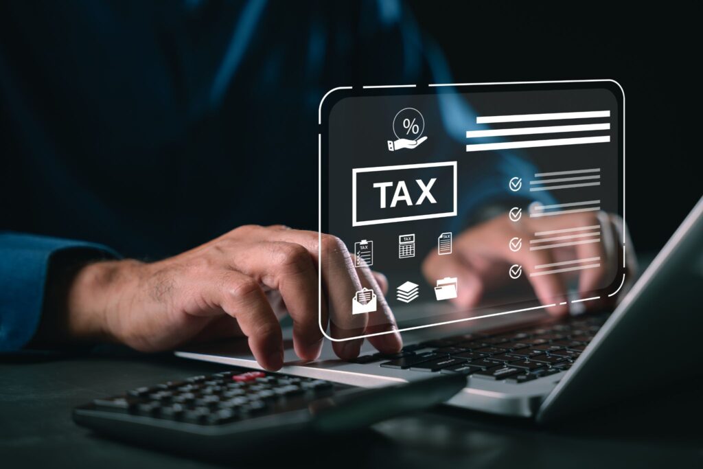 A close-up of a person typing on a laptop with a calculator in the foreground, featuring a digital graphic overlay of tax icons and checklists.