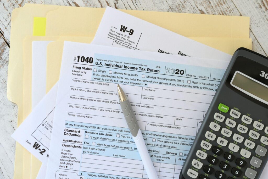 Tax forms and a calculator arranged on a desk indicating preparation for tax filing or financial planning